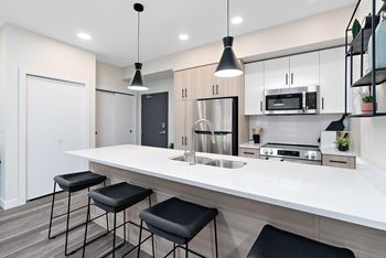 A modern kitchen with a white countertop and black bar stools.